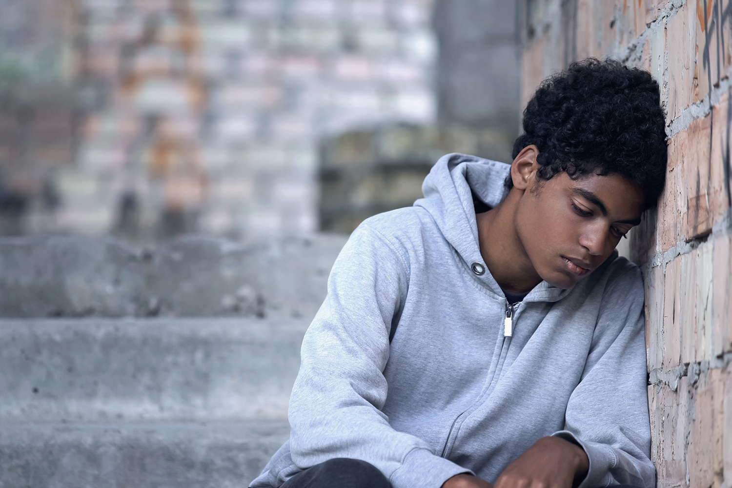 Teenager leaning against brick wall