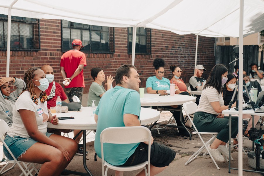 crowd sitting around tables under a tent