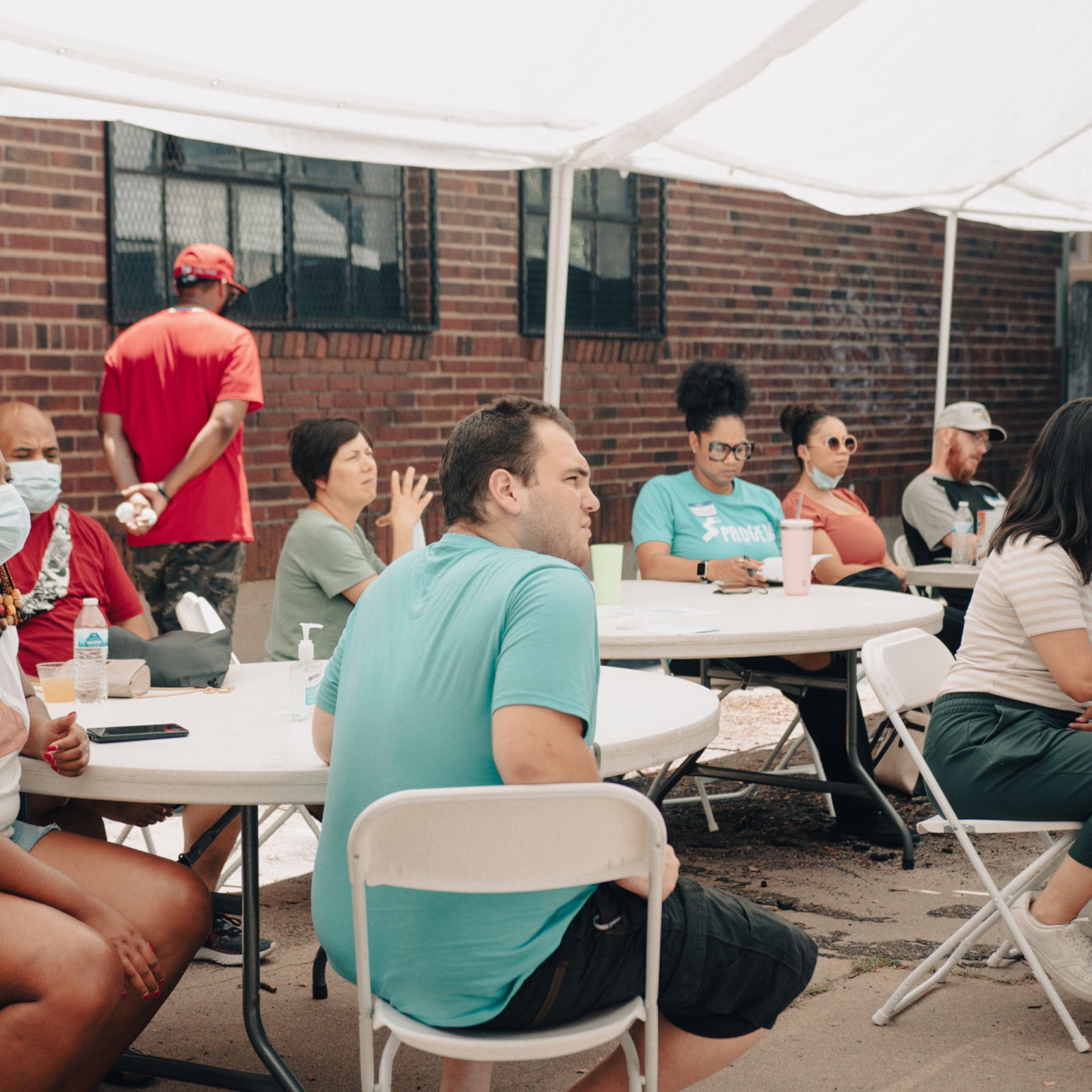 crowd sitting around tables under a tent